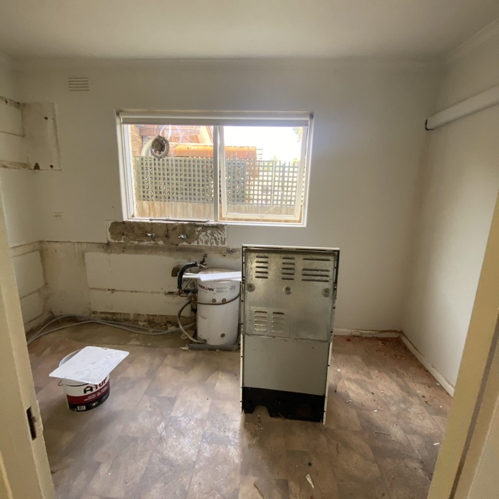 A room before renovation with damaged walls and clutter