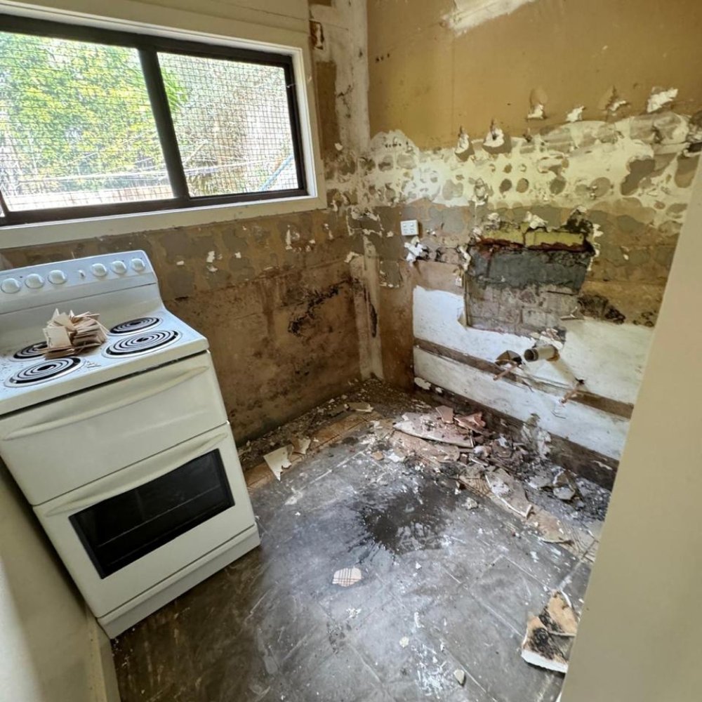 Damaged wall with visible cracks, peeling paint, and chipped plaster before renovation