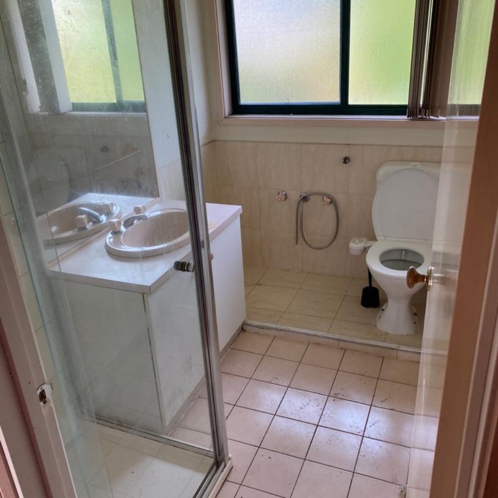 athroom with chipped tiles and old fixtures before being renovated