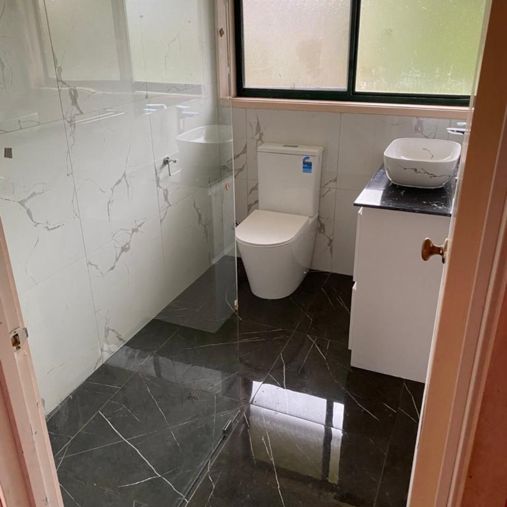 Stylish bathroom remodeling with a large mirror, updated lighting, and a clean, open layout.