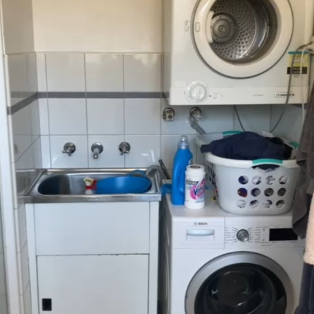 Outdated laundry room with worn appliances and limited storage